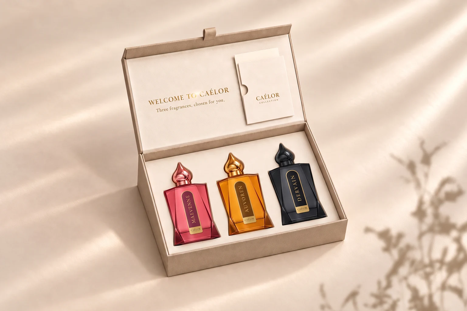 Open beige CAÉLOR gift box holding three perfume bottles on softly lit cream fabric